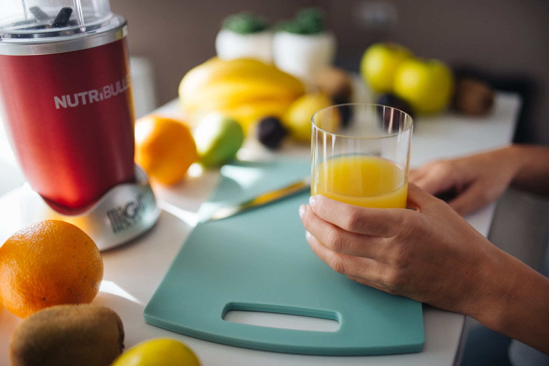 préparation d'un jus de fruits frais à l'extracteur dans une cuisine, verre rempli et fruits sur le plan de travail