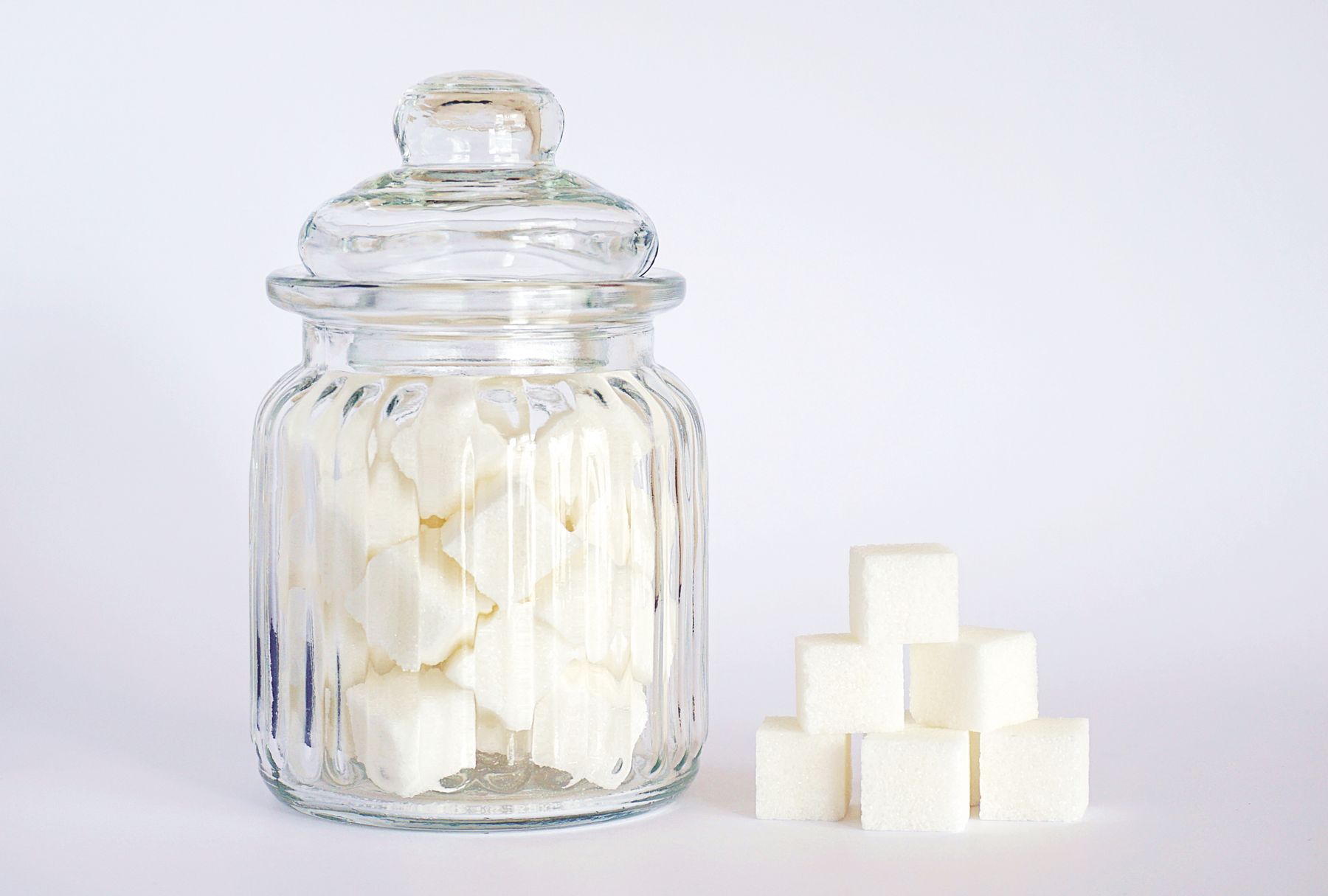 bocal en verre rempli de sucres en morceaux, avec une petite pile de morceaux posée à côté