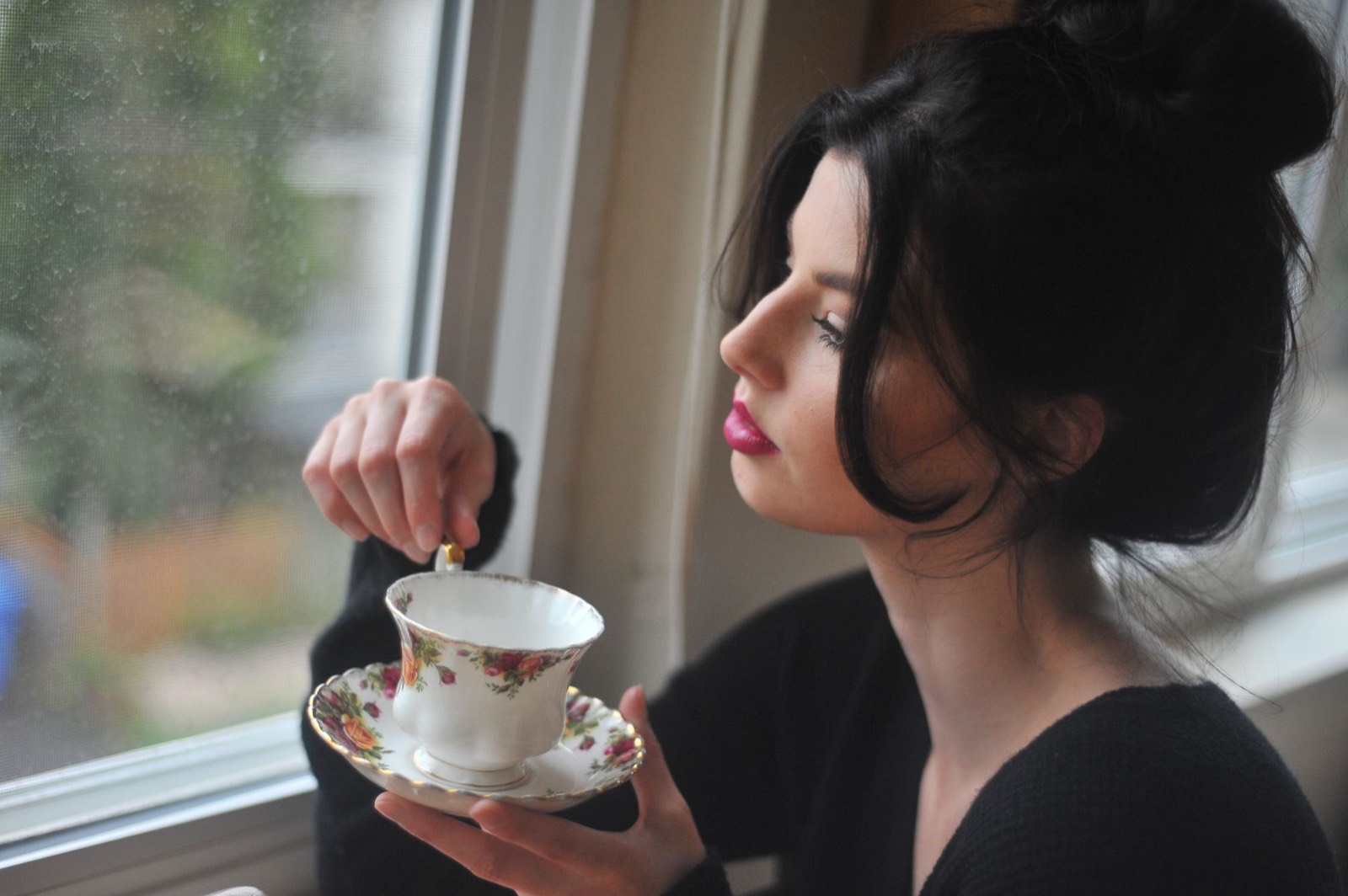 Femme devant une fenêtre le matin avec une tasse, moment calme propice à une prise de gouttes