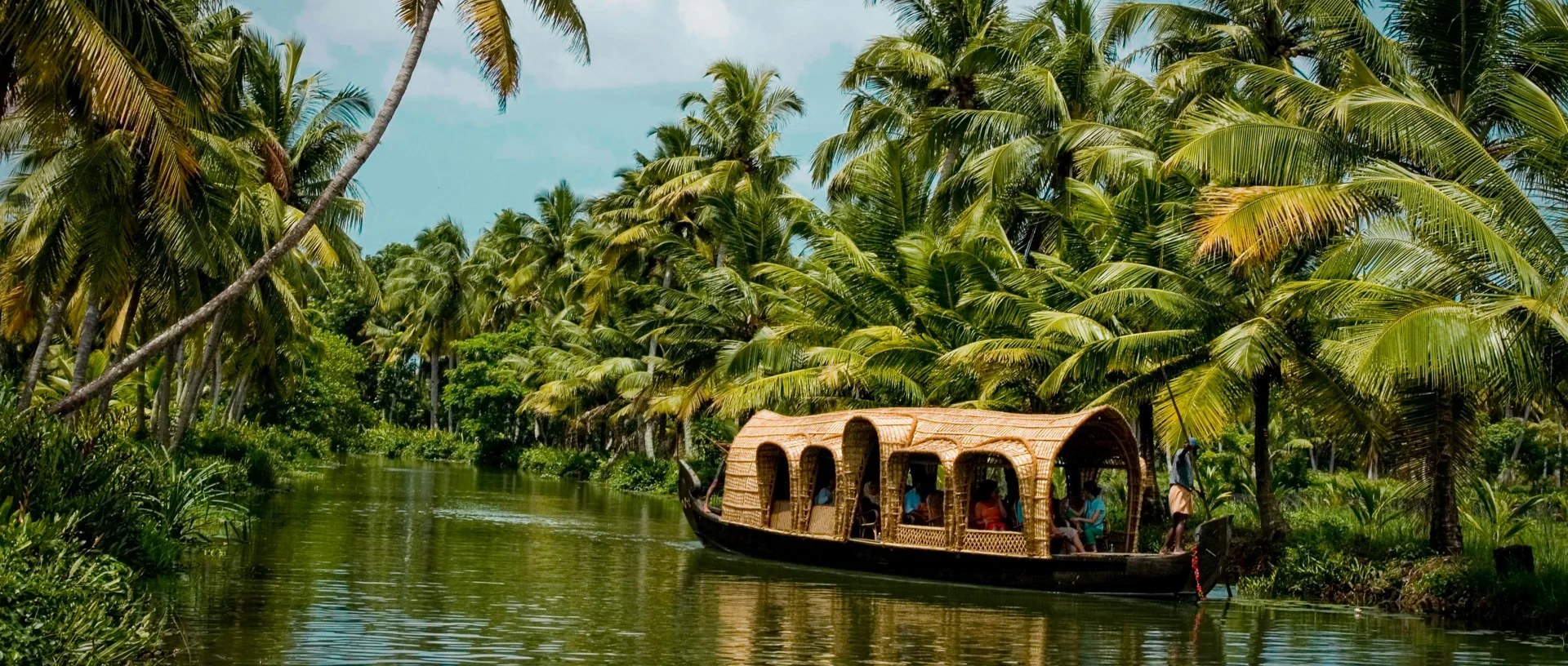 Bateau traditionnel en bambou tressé glissant sur les backwaters du Kerala entourés de palmiers